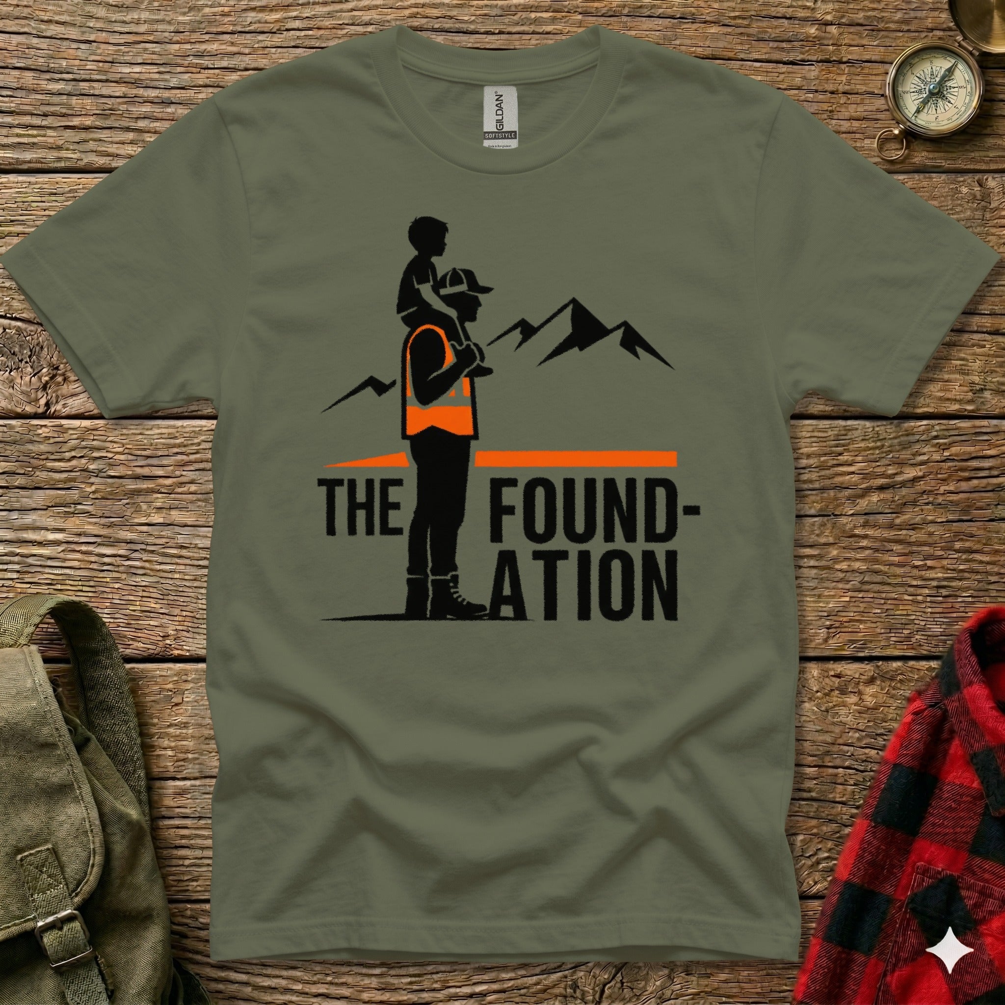 T-shirt with graphic of man carrying child, mountains, and "The Foundation" text.