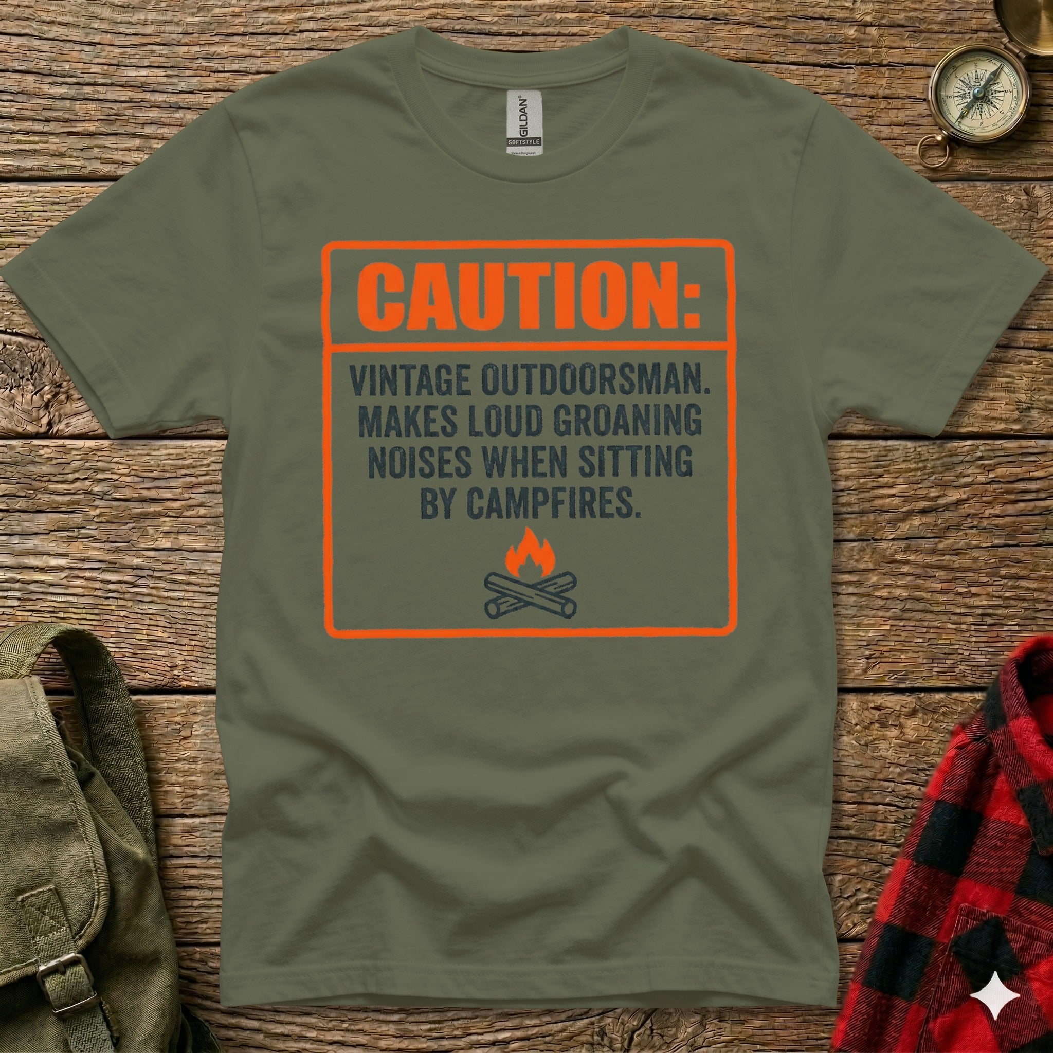 Green t-shirt with orange text: "CAUTION: VINTAGE OUTDOORSMAN. MAKES LOUD GROANING NOISES WHEN SITTING BY CAMPFIRES."