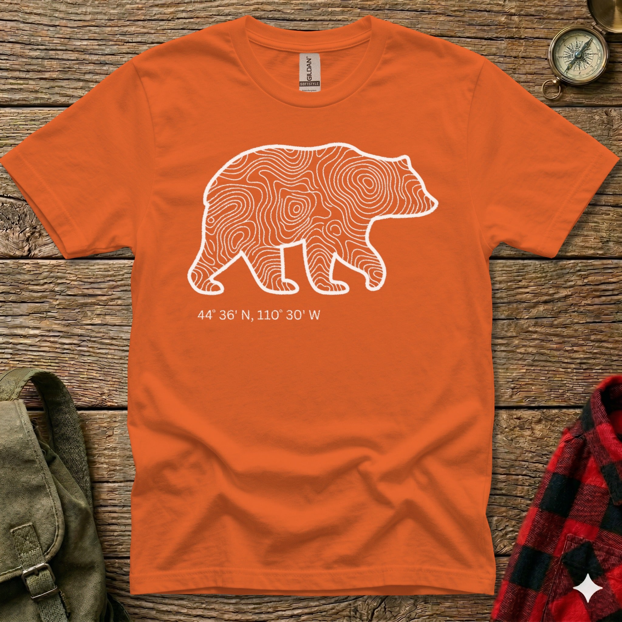 Orange t-shirt with white bear silhouette filled with topographic lines and coordinates.