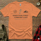 Orange t-shirt with compass, boot print, and mountain graphic, reading "DIRECTION FIRST COMFORT LAST".