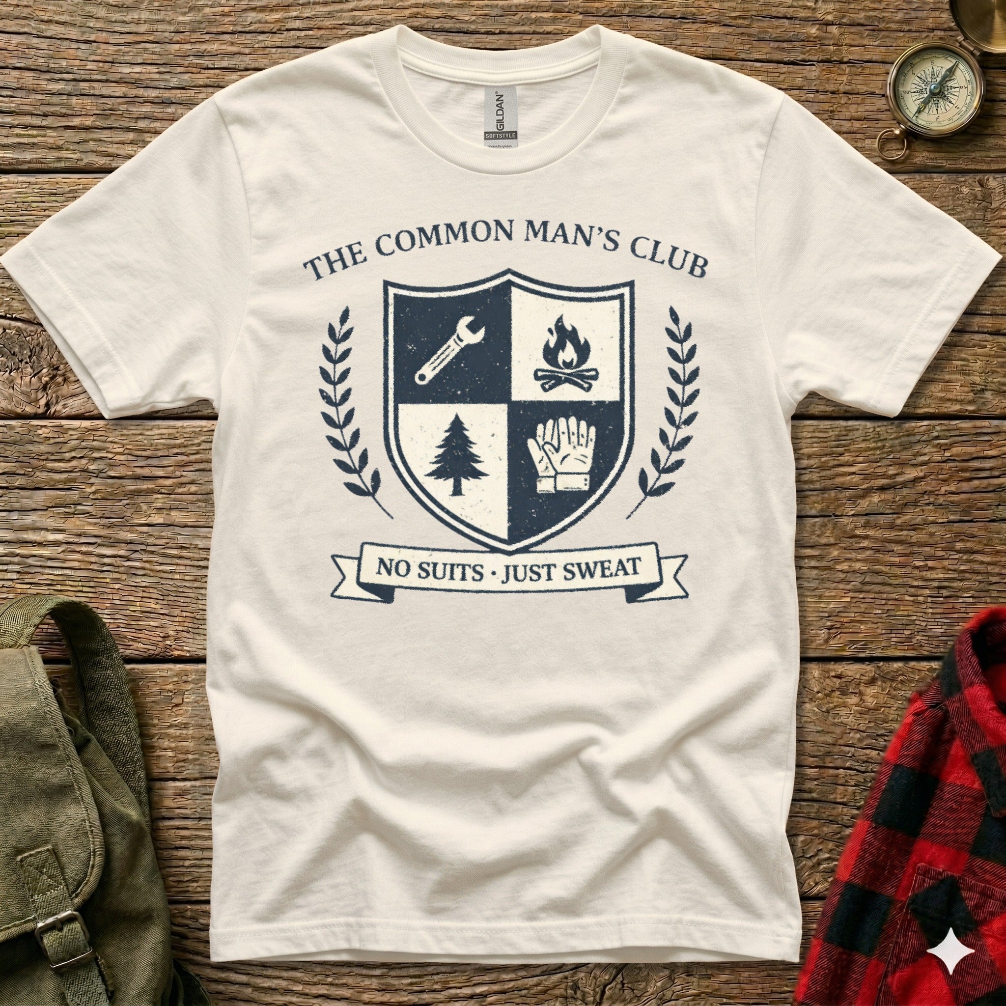Cream t-shirt with "The Common Man's Club" crest featuring shield, tree, and gloves.