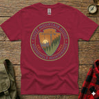 Crimson t-shirt with circular "Chief Mountain Guide Household Maintenance" logo and "Est. 1985" text.