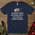Navy t-shirt with fishing graphic and text: "My wife thinks I'm fixing stuff... I'm actually going fishing."