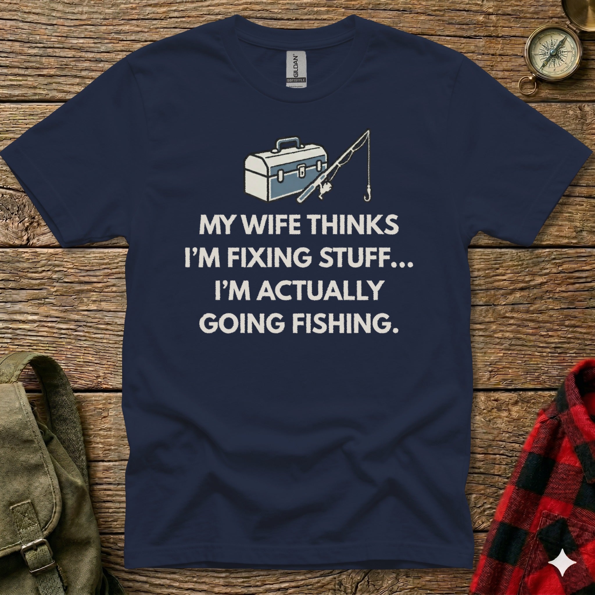 Navy t-shirt with fishing graphic and text: "My wife thinks I'm fixing stuff... I'm actually going fishing."